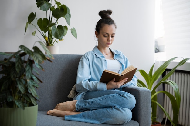 Mujer de tiro completo leyendo en el sofá