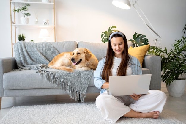 Mujer de tiro completo y lindo perro en el interior