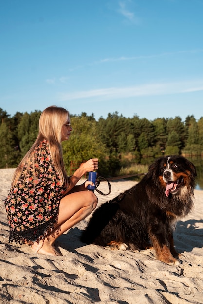Mujer de tiro completo con lindo perro en la playa