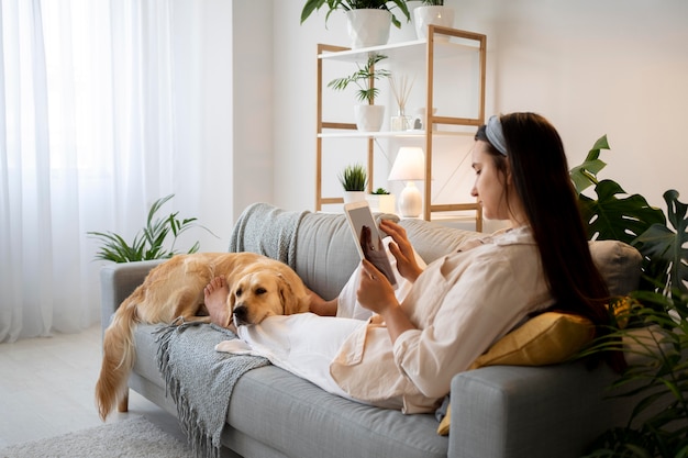 Mujer de tiro completo y lindo perro en el sofá