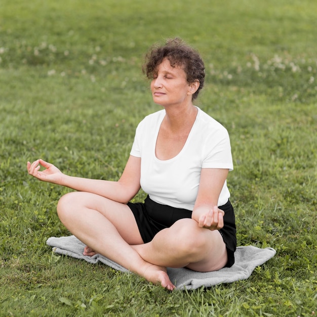 Mujer de tiro completo meditando al aire libre