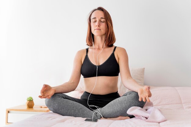 Mujer de tiro completo meditando en la cama