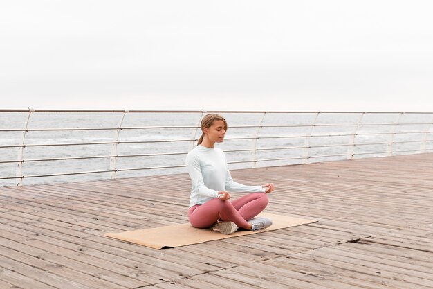 Mujer de tiro completo meditando en estera