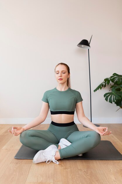 Mujer de tiro completo meditando sobre estera