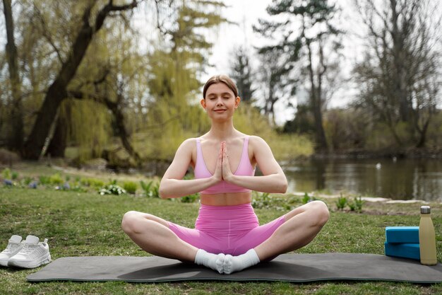 Mujer de tiro completo meditando sobre estera