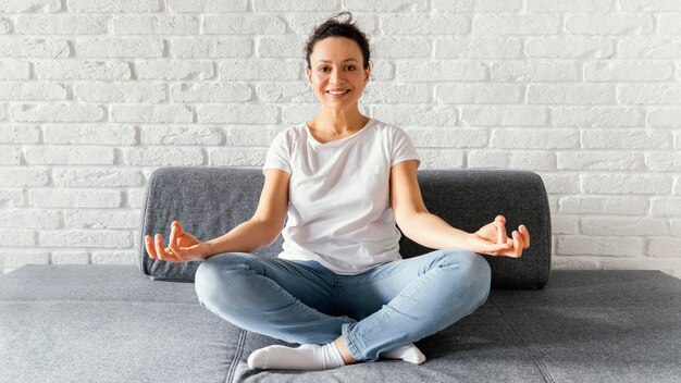 Mujer de tiro completo meditando en el sofá