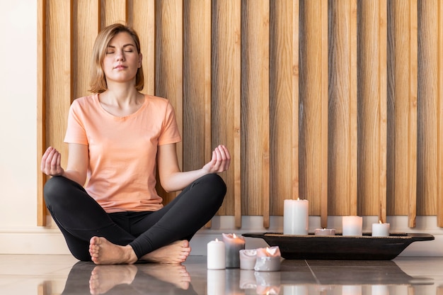 Mujer de tiro completo meditando con velas