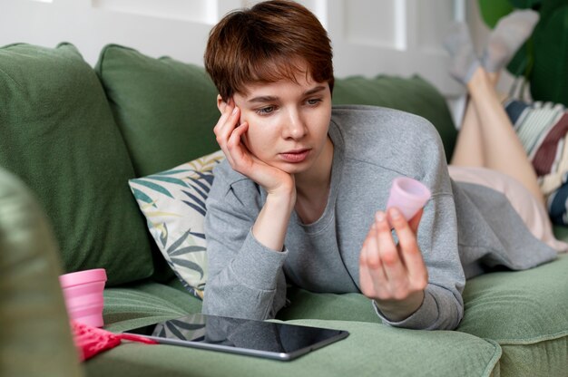 Mujer de tiro completo mirando la copa menstrual