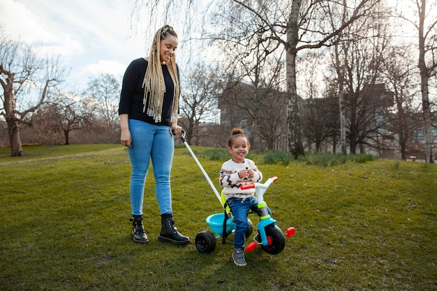 Mujer de tiro completo y niña sonriente en el parque