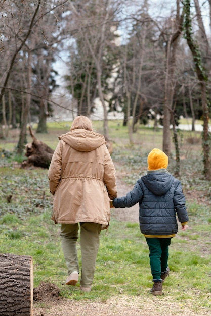 Mujer de tiro completo y niño caminando juntos