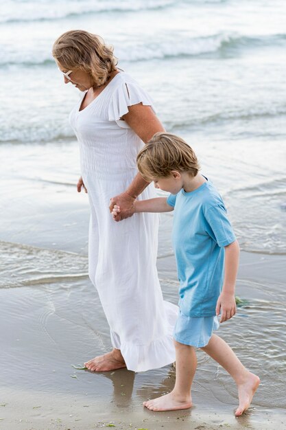 Mujer de tiro completo y niño caminando en la playa