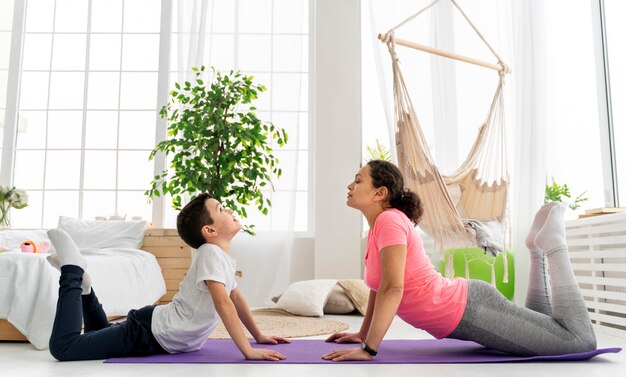 Mujer de tiro completo y niño en estera de yoga