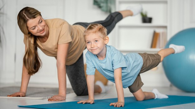 Mujer de tiro completo y niño haciendo ejercicio juntos