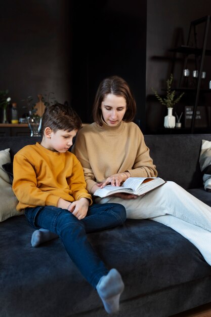 Mujer de tiro completo y niño leyendo la biblia