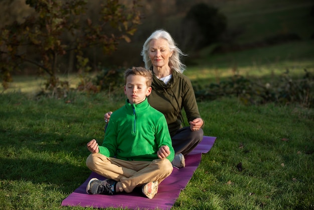 Foto gratuita mujer de tiro completo y niño meditando fuera