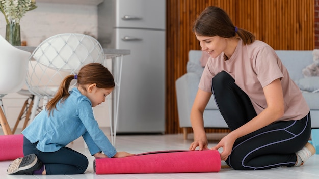 Foto gratuita mujer de tiro completo y niño con tapete