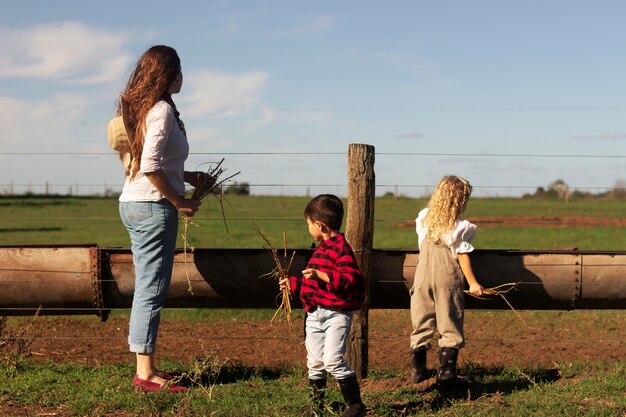 Mujer de tiro completo y niños en la naturaleza.