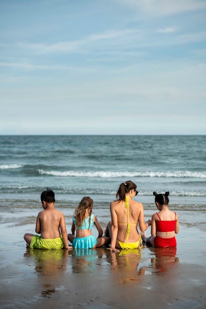 Foto gratuita mujer de tiro completo y niños en la playa.