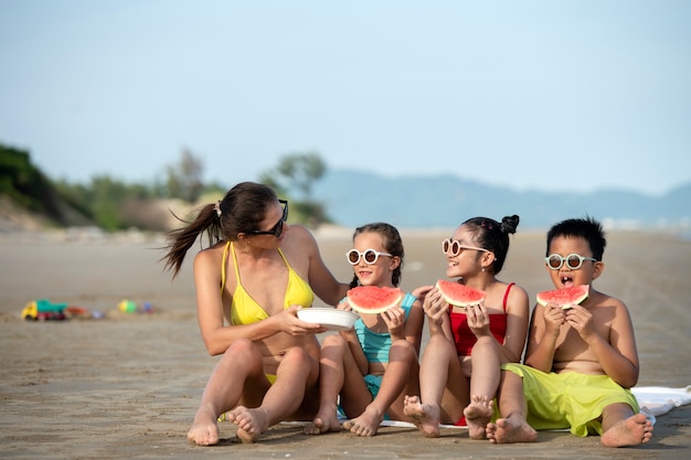 Foto gratuita mujer de tiro completo y niños con sandía.