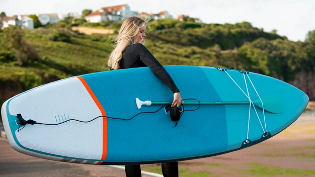 Mujer de tiro completo con paddleboard