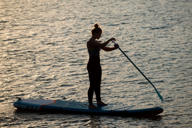 Mujer de tiro completo paddleboarding