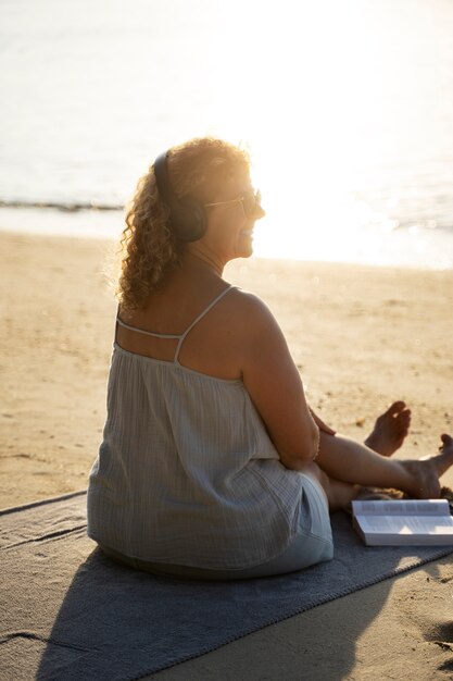 Mujer de tiro completo pasando un día sola en la playa.