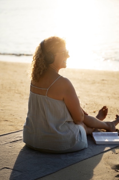 Mujer de tiro completo pasando un día sola en la playa.