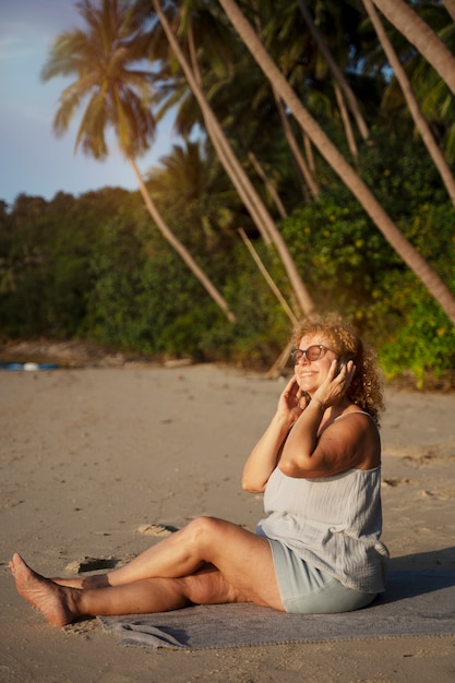 Mujer de tiro completo pasando un día sola en la playa.