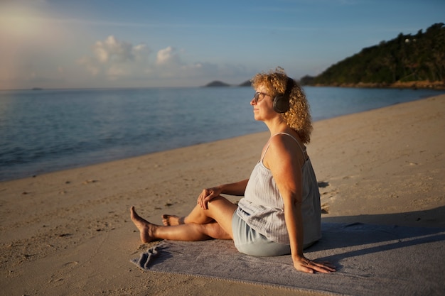 Mujer de tiro completo pasando un día sola en la playa.