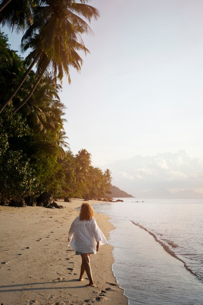 Mujer de tiro completo pasando un día sola en la playa.