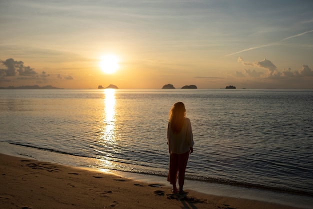 Mujer de tiro completo pasando un día sola en la playa.