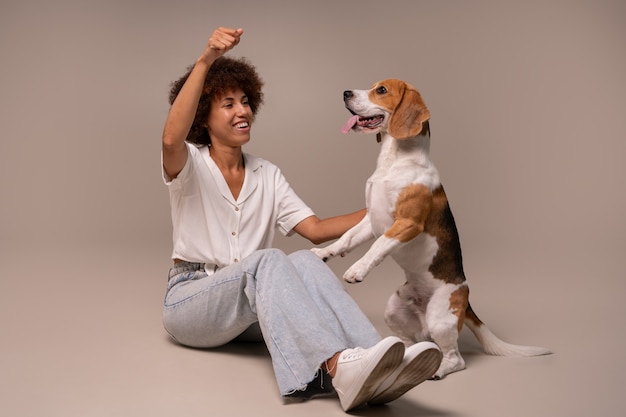 Foto gratuita mujer de tiro completo con perro en estudio