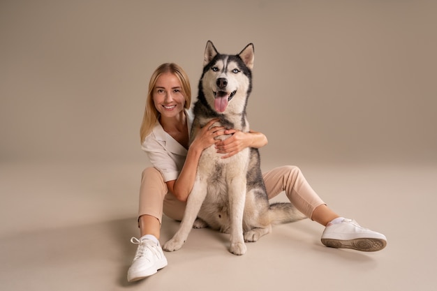 Foto gratuita mujer de tiro completo con perro en estudio