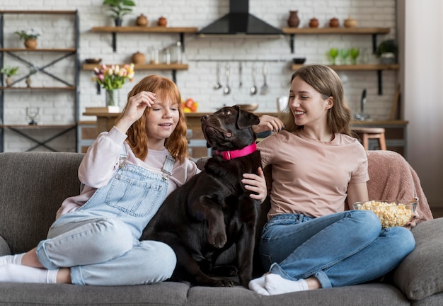 Mujer de tiro completo y perro sentados juntos