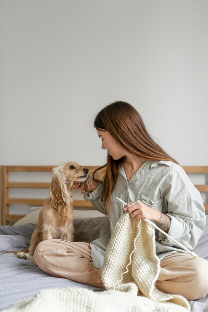 Mujer de tiro completo con perro tejiendo