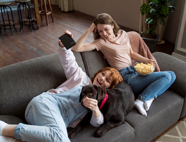 Foto gratuita mujer de tiro completo y perro tomando selfie