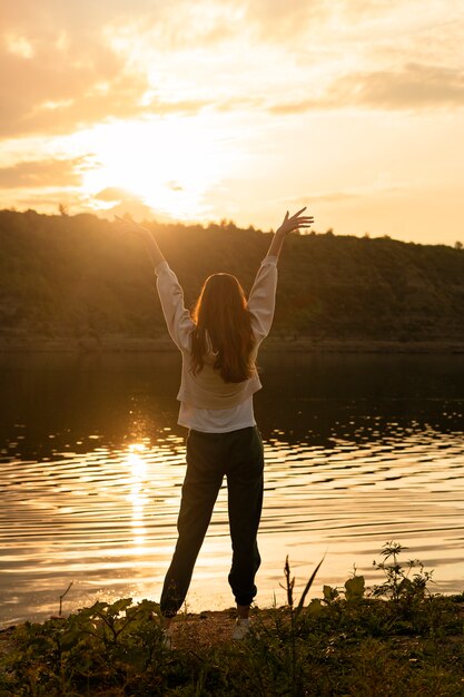 Mujer de tiro completo de pie junto al lago