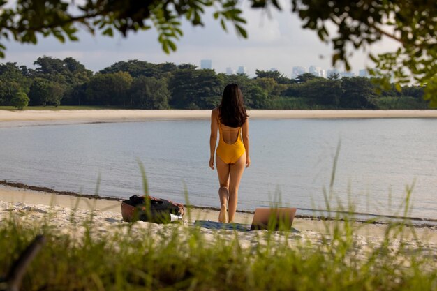 Mujer de tiro completo en la playa con portátil