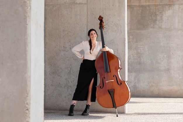 Mujer de tiro completo posando con contrabajo