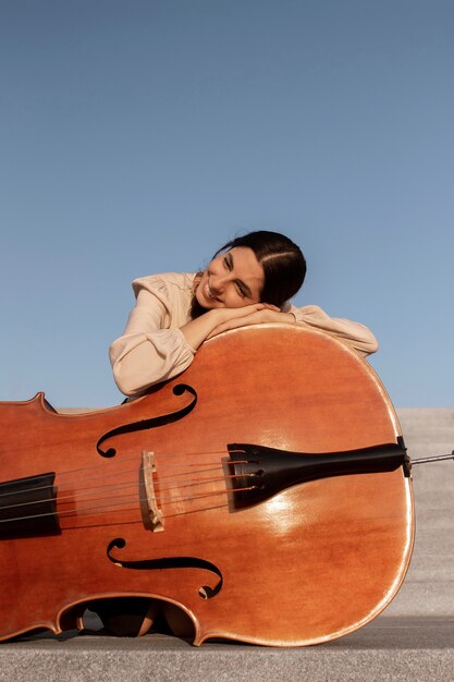 Mujer de tiro completo posando con contrabajo