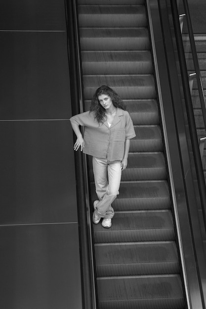 Foto gratuita mujer de tiro completo posando en las escaleras en blanco y negro