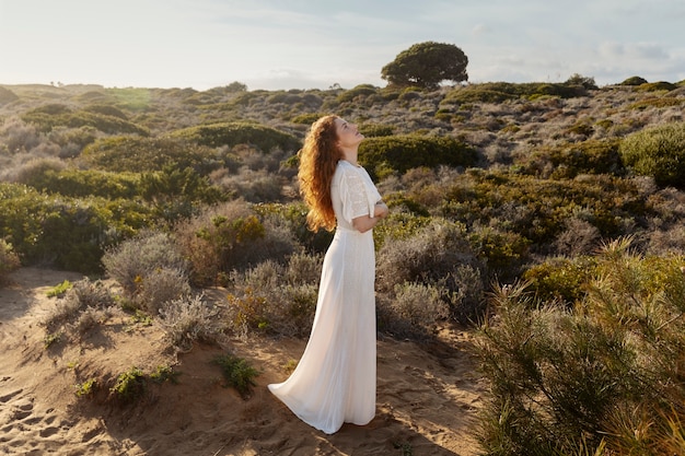 Mujer de tiro completo posando en vestido blanco