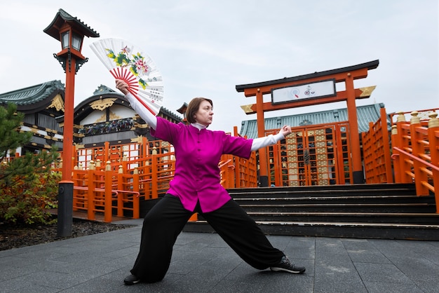 Mujer de tiro completo practicando tai chi