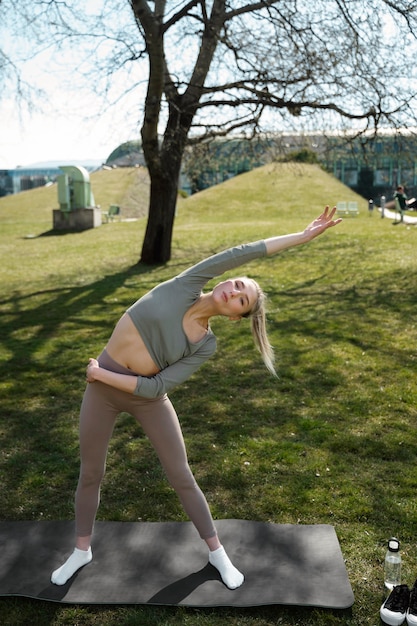 Mujer de tiro completo que se extiende al aire libre