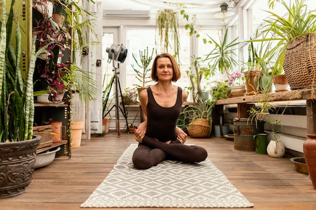 Mujer de tiro completo que se extiende cerca de las plantas