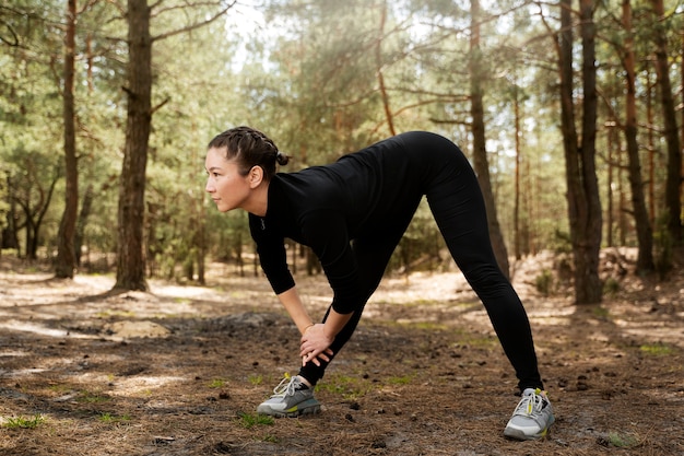 Mujer de tiro completo que se extiende en la naturaleza