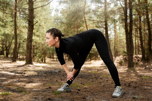 Mujer de tiro completo que se extiende en la naturaleza