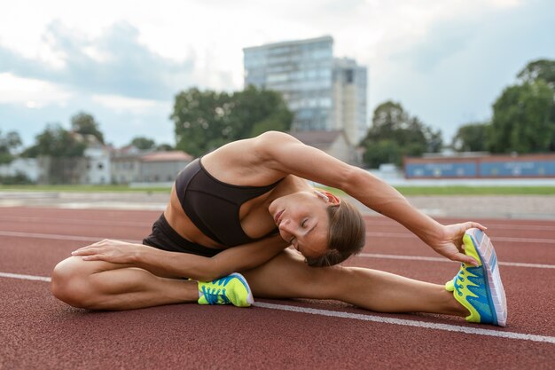 Mujer de tiro completo que se extiende en la pista