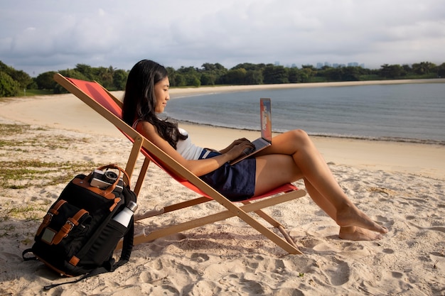 Mujer de tiro completo que trabaja en la computadora portátil al aire libre