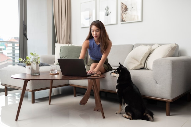 Mujer de tiro completo que trabaja en la computadora portátil con el perro